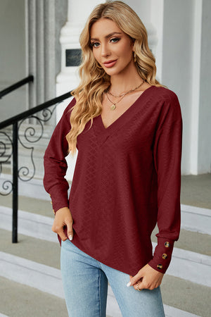 Burgundy diamond-textured V-neck blouse with button cuffs and long sleeves.