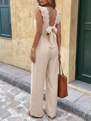 Beige ruffled V-neck wide-leg romper with lace trim and back bow tie detail.