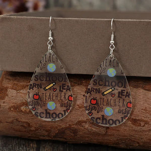 Schoolhouse graphic teardrop earrings in transparent acrylic with teacher-themed print.