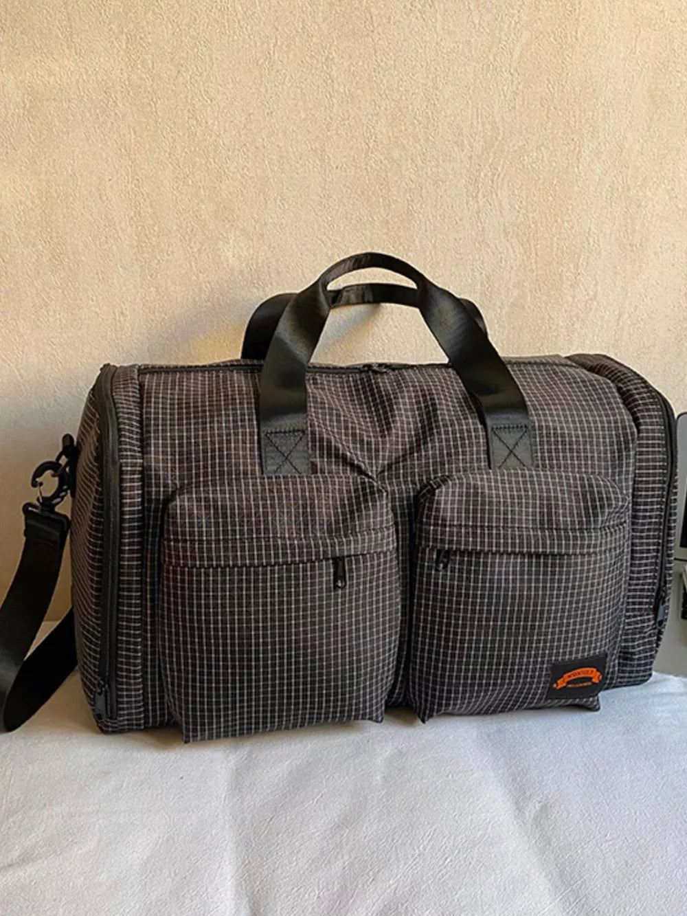 Chic medium plaid duffel bag with two front pockets and adjustable strap.