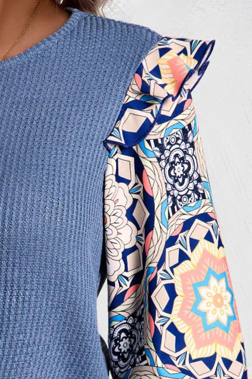 Dusty blue knit top with ruffled printed sleeves and a boho pattern.