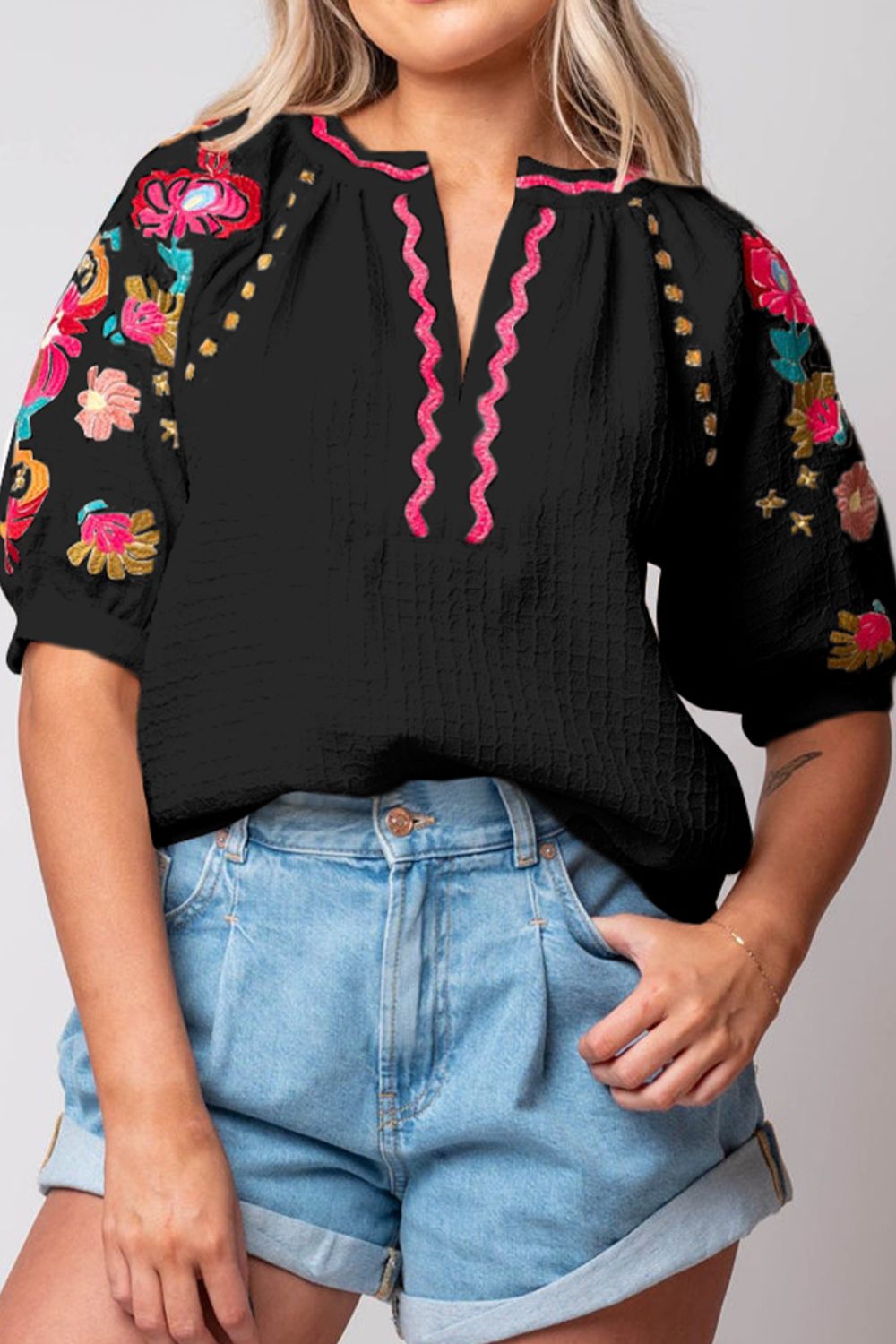 Black blouse with embroidered floral sleeves and pink zigzag neckline detail