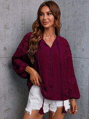 Textured wine tie-neck blouse with lace trim and tassel details.