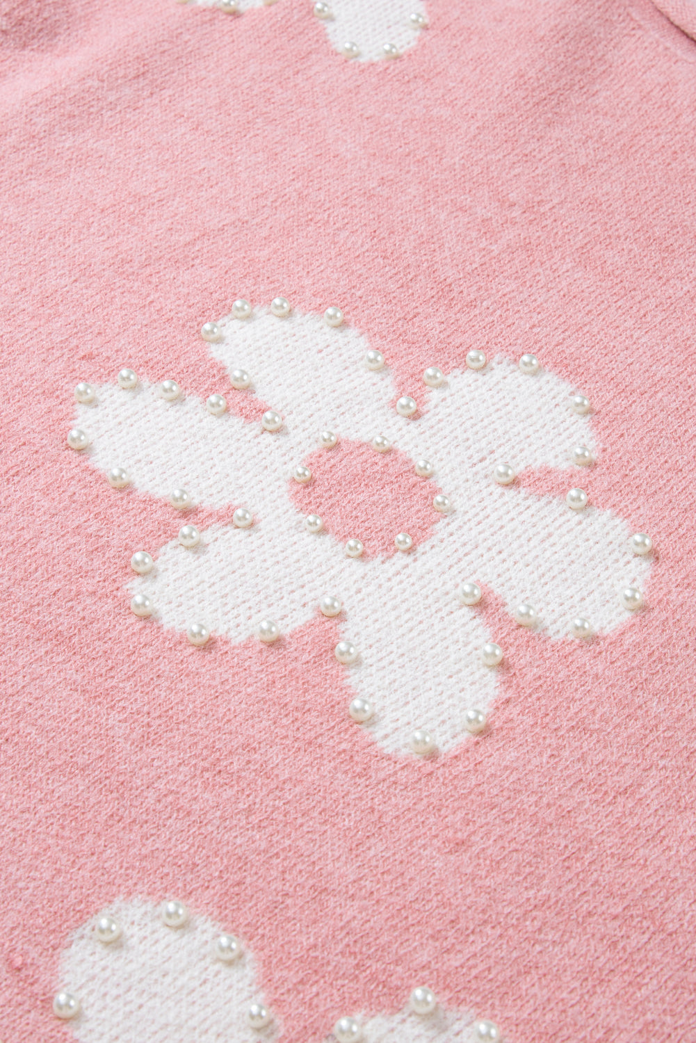 Blush pink knit sweater with white floral pattern embellished with pearls.