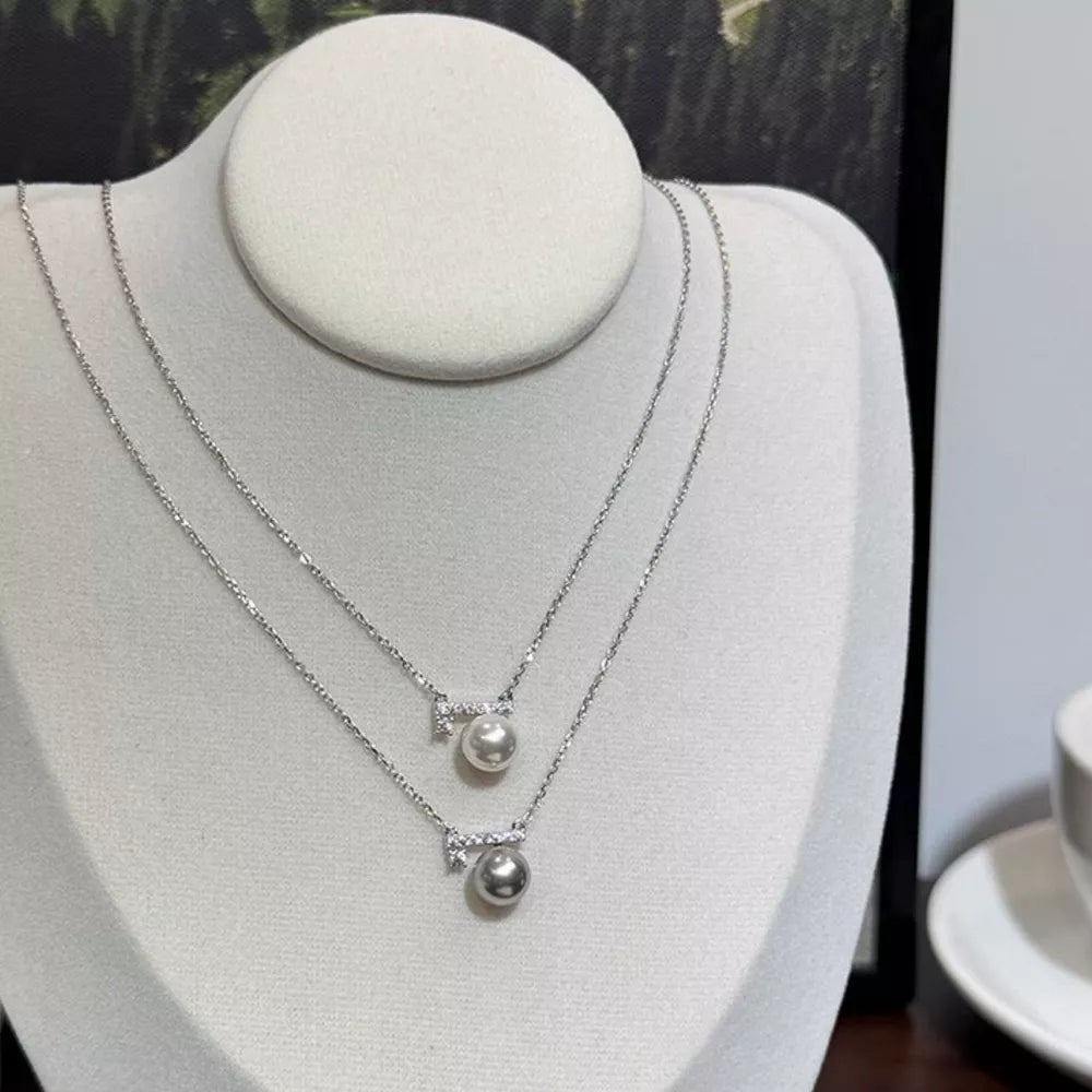 Lustrous pearl pendant necklaces with zircon accents, one light gray pearl, one cream pearl.