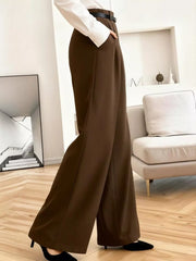 Brown high-waisted pleated wide leg maternity trousers with a belt and pockets.