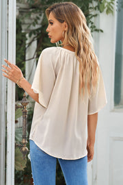 Relaxed V-neck blouse in cream with cap sleeves and gathered neckline detail.