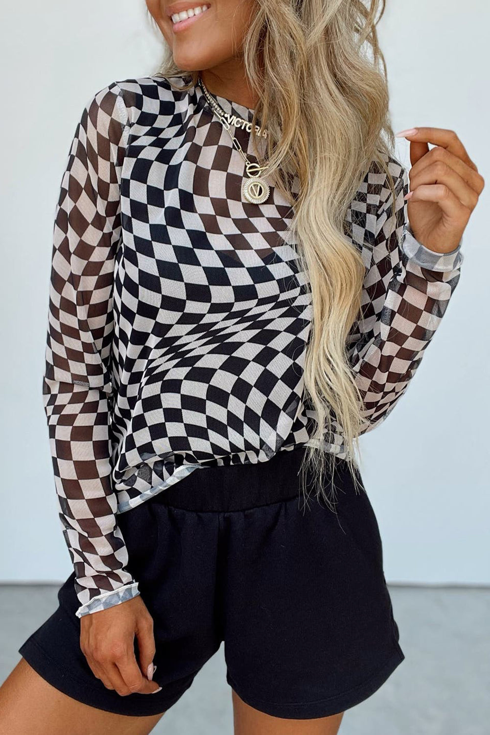 Black and white checkered mesh blouse with long sleeves and a mock neck.