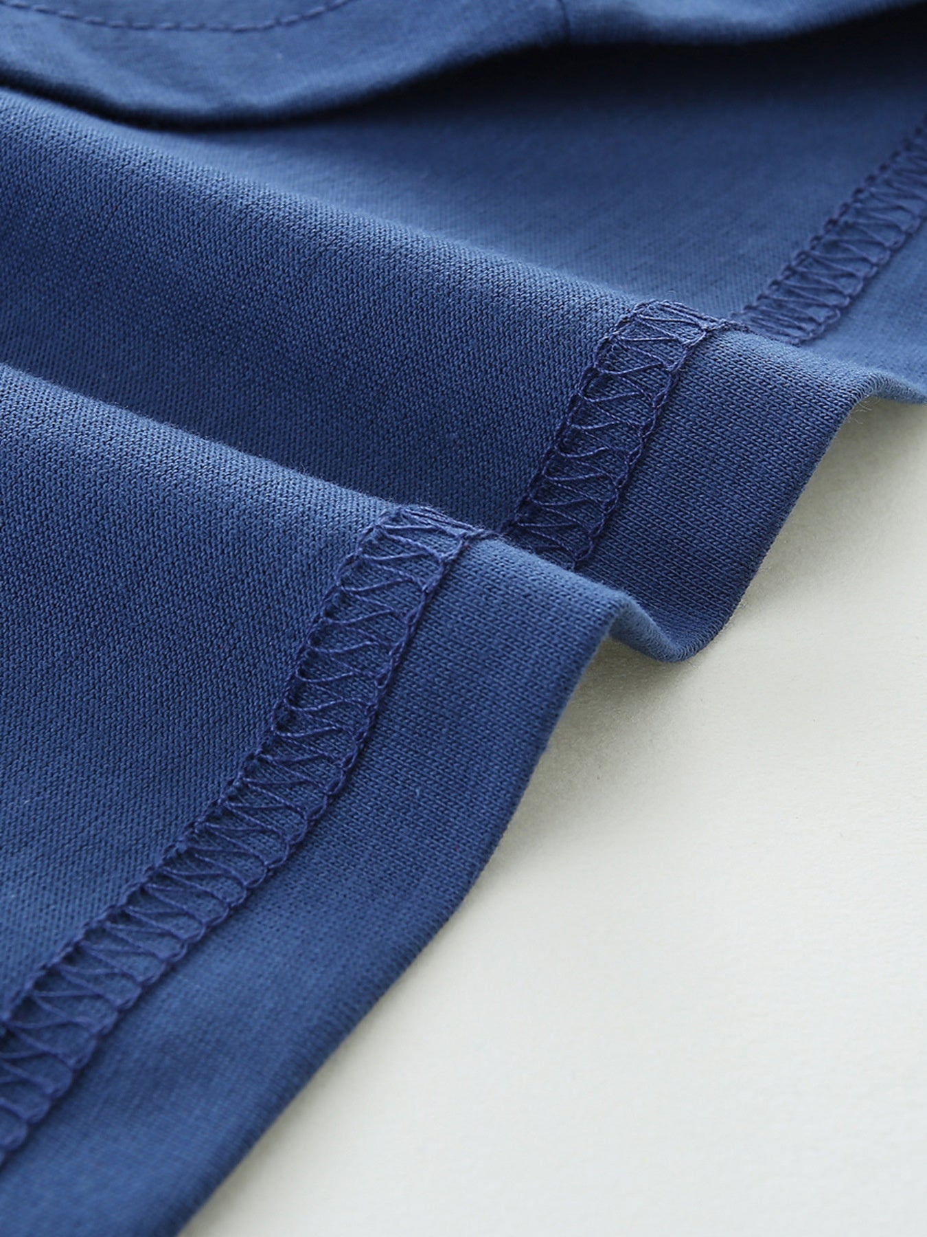 Blue cotton t-shirt detail showing hem stitching and fabric texture