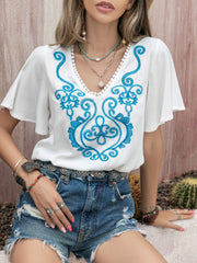 White embroidered blouse with flutter sleeves and V-neckline.