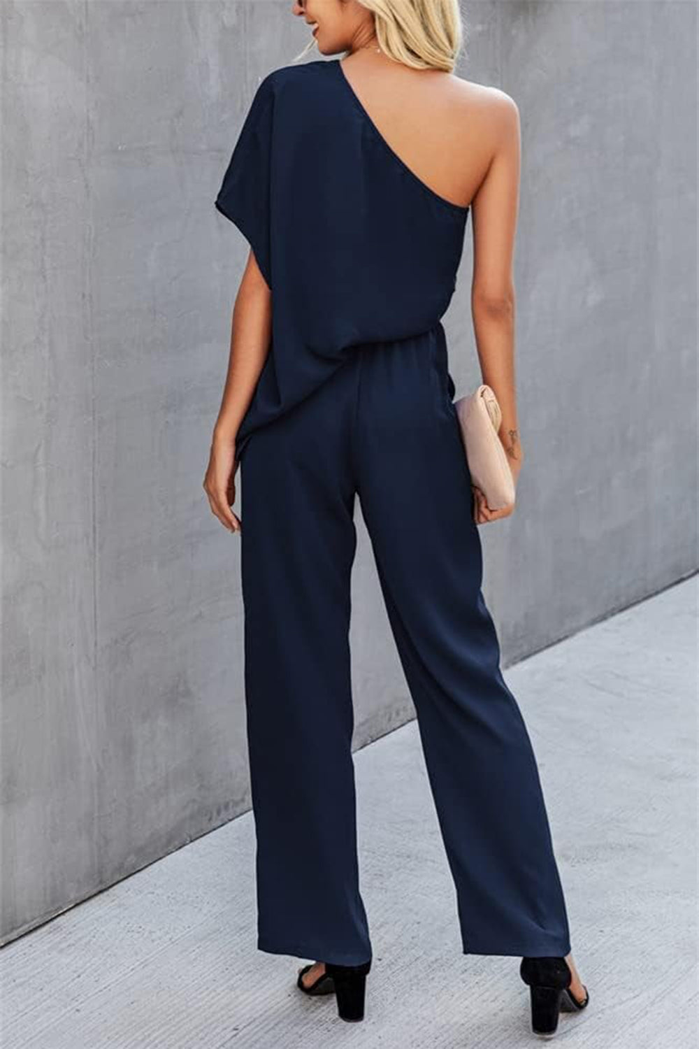Dark blue asymmetric drape-sleeve wide-leg jumpsuit with elastic waist.