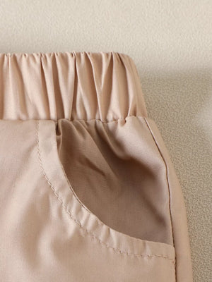 Baby shorts with elastic waist and pocket detail in tan cotton.