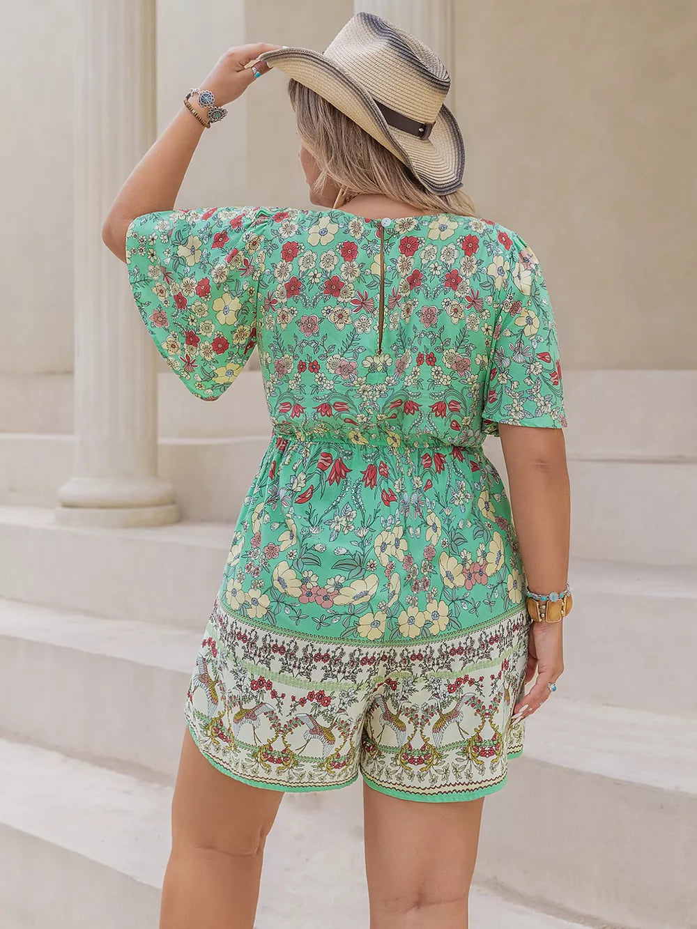 Plus-size green floral romper with cinched waist and short flutter sleeves.