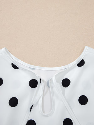 White polka dot blouse with tie-neck detail and smocked cuffs.