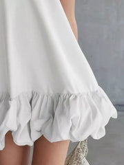 White V-neck mini dress with bubble hem detail and ruffled trim.