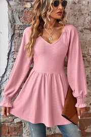 Blush pink textured blouse with V-neck, empire waist, and shirred long sleeves.