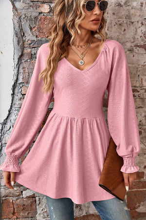 Blush pink textured blouse with V-neck, empire waist, and shirred long sleeves.