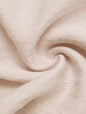Luxe ruffled V-neck wide-leg romper in textured cream fabric.