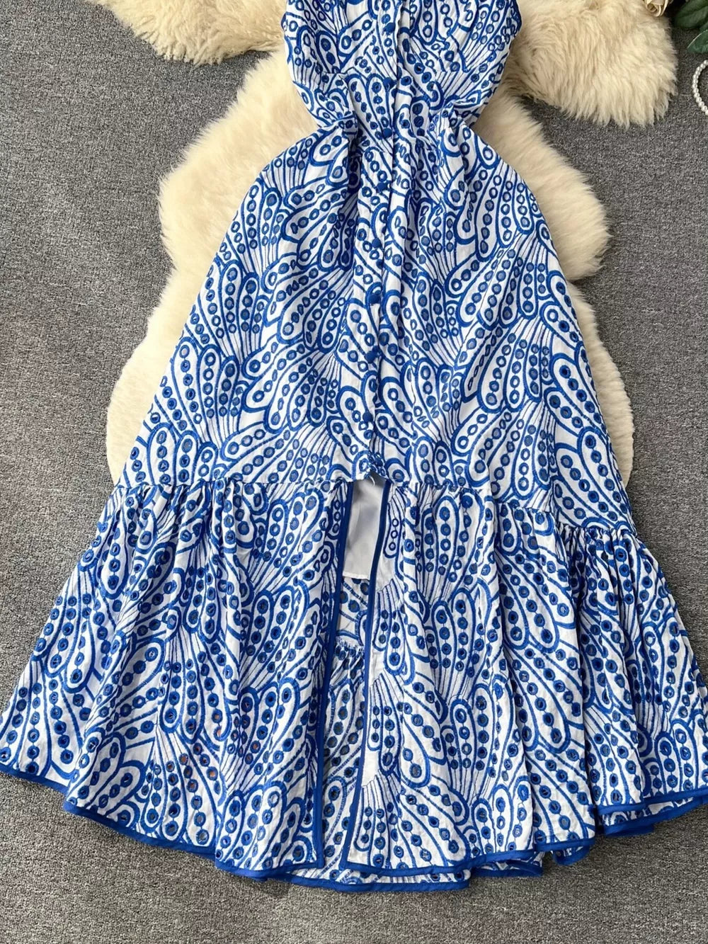 Blue and white lace-embroidered tiered cami dress with cutout detail and ruffled hem.