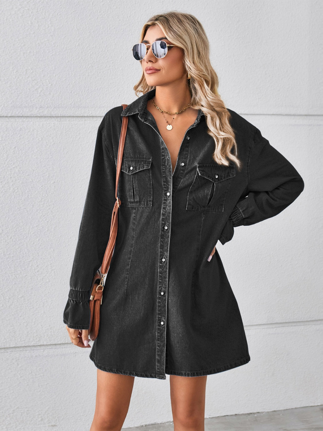 Black oversized denim shirt dress with button front, chest pockets, and cuffed sleeves.