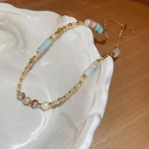 Multi-strand gemstone collar necklace with beads, pearls, and blue accents.