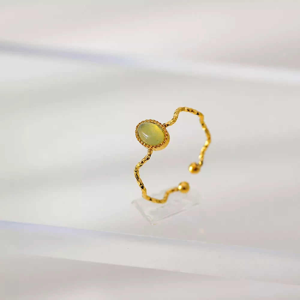 Wavy gold-plated ring with oval light green natural stone and adjustable band.