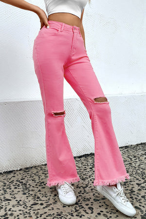 Pink distressed flare denim jeans with raw hem and knee rips