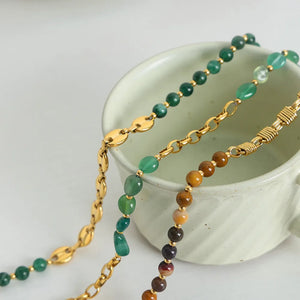 Gilded bead and chain statement necklace with green and mustard colored stones.