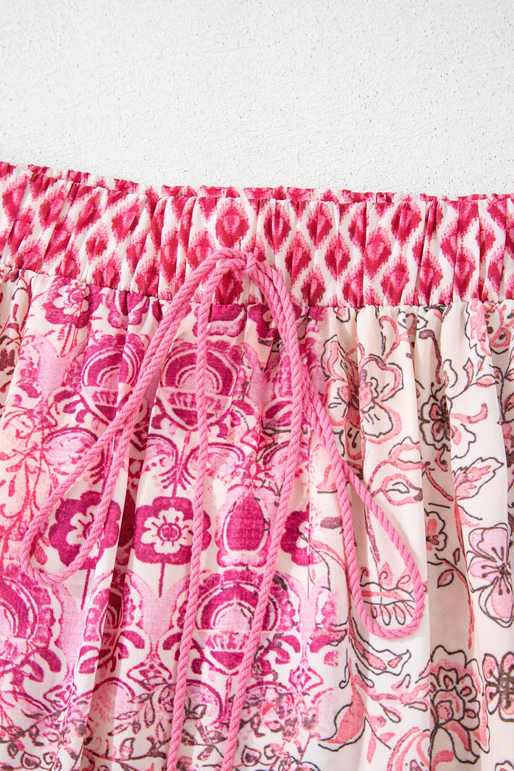 Printed tiered maxi skirt in dusty pink with a drawstring and tassel detail.