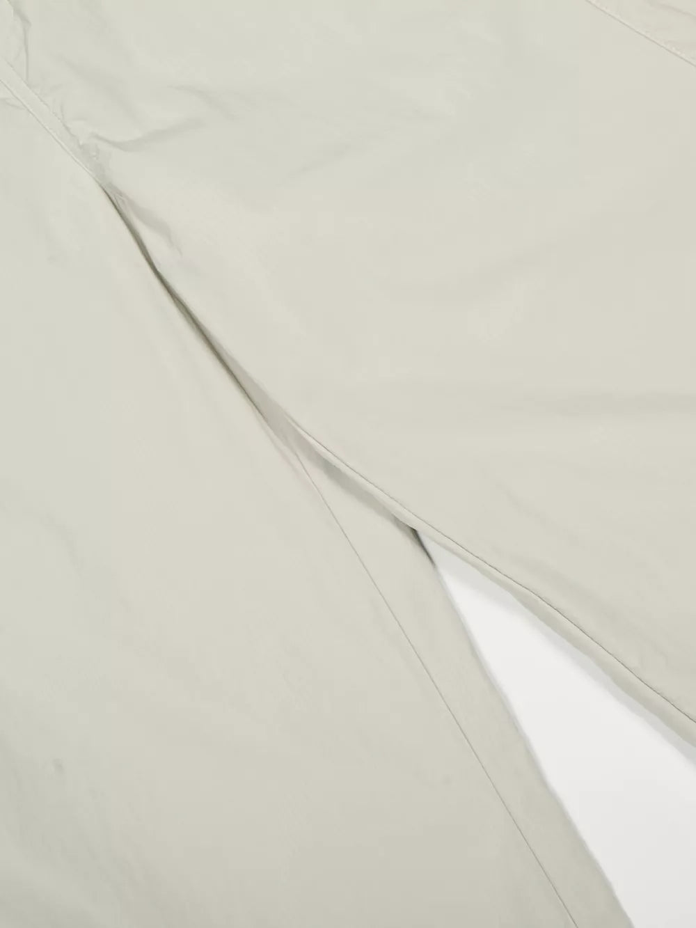 Men's light gray wide-leg sweatpants detail showing crinkled fabric and seam.