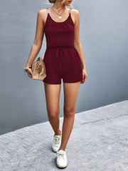 Burgundy chain-strap drawstring romper with cinched waist and gold hardware detail.