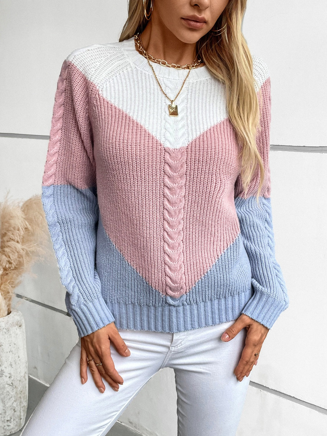 Chevron cable knit sweater in pastel blue, blush pink, and white with a V-shaped colorblock design.