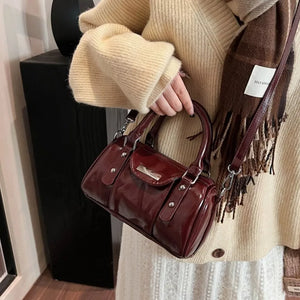 Elegant barrel crossbody bag in wine red with top handles and silver hardware.