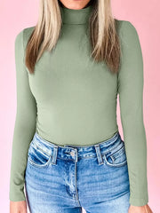 Stretchy long-sleeve turtleneck tunic in sage green, styled with blue jeans.