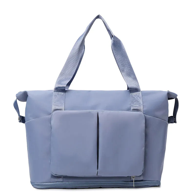 Light blue foldable travel tote bag with exterior pockets and zippered bottom
