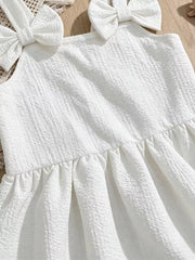 White baby dress with textured fabric, bowknot shoulder straps, and ruffle hem.