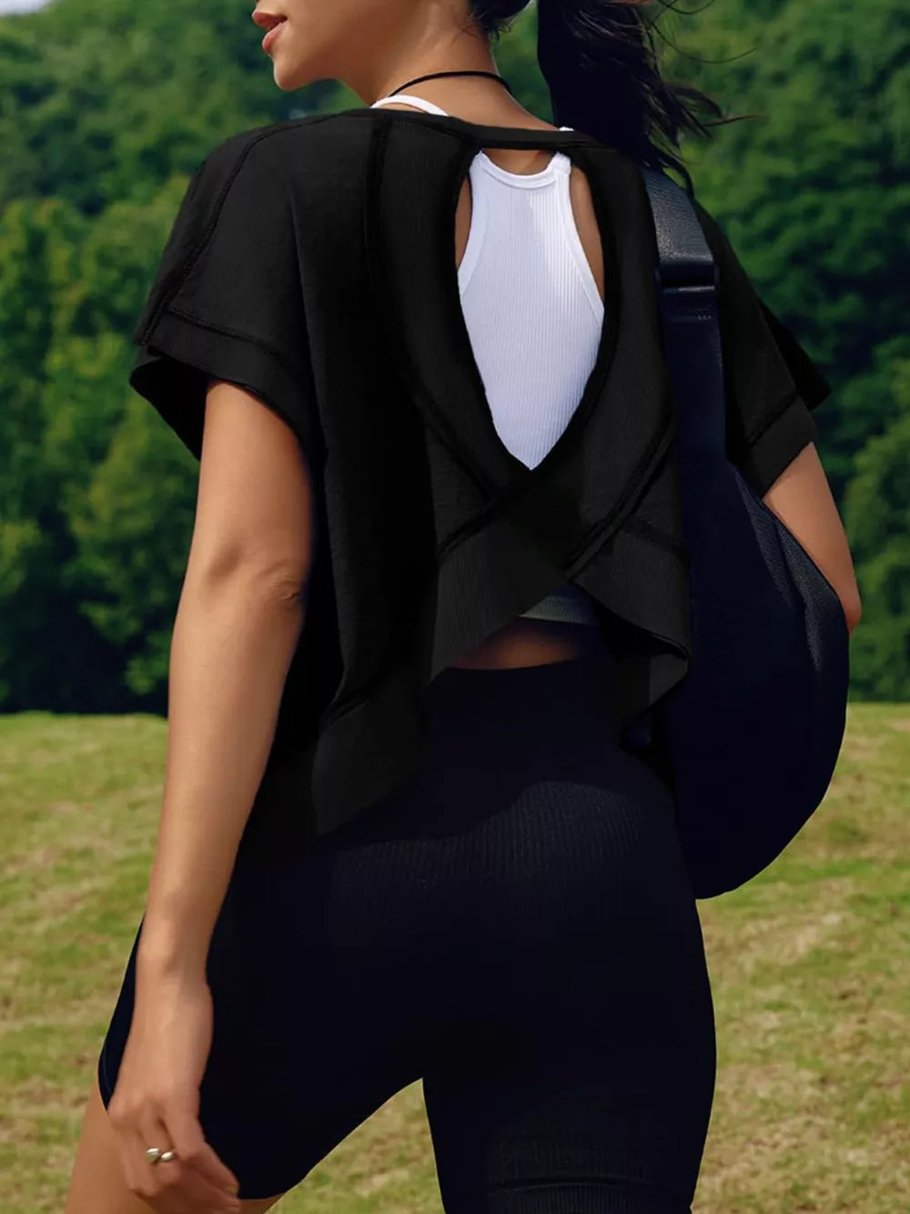 Black t-shirt with exposed seams and a cutout back, layered over a white tank top.