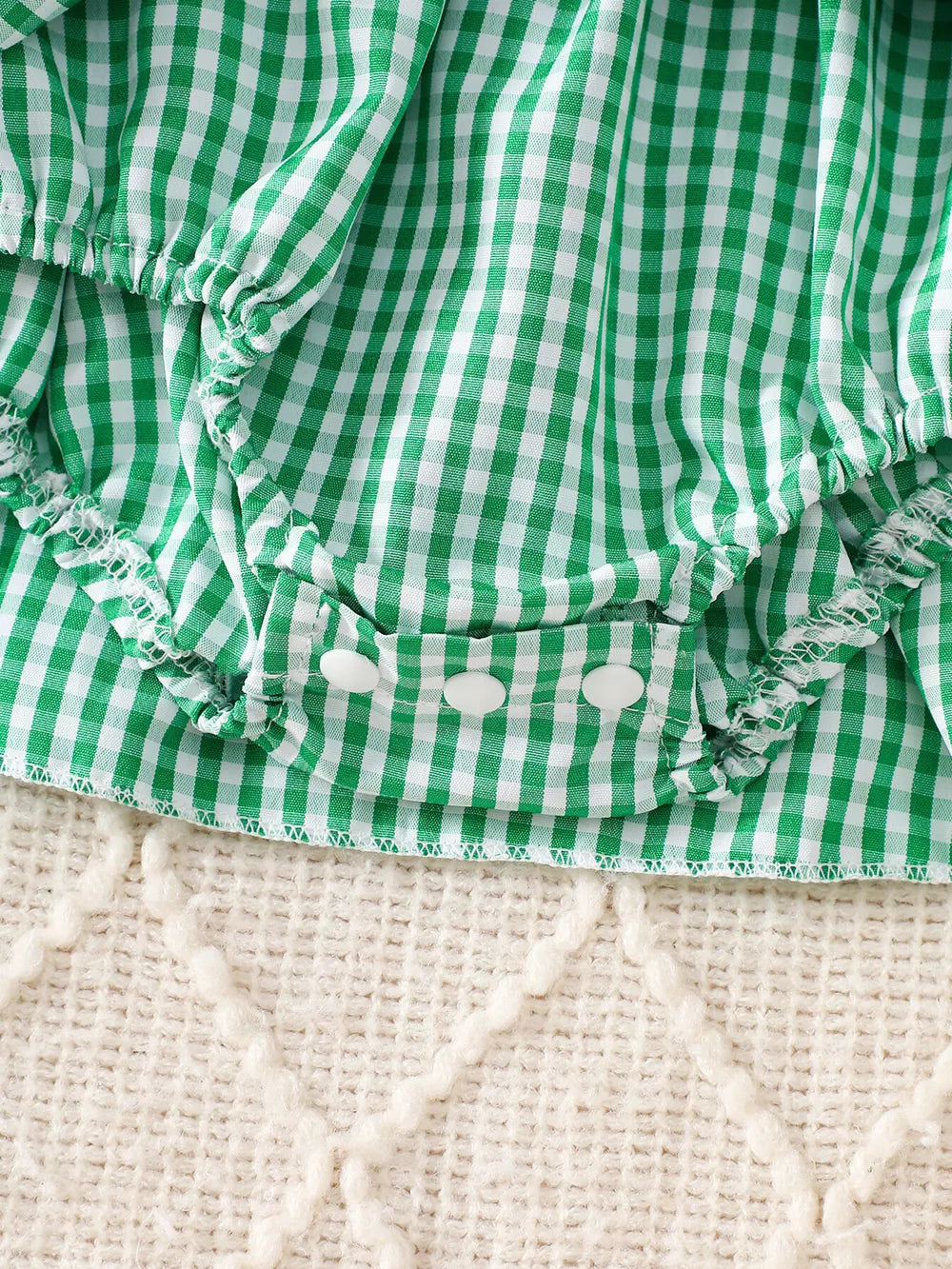 Green gingham baby one-piece with white buttons and ruffled trim