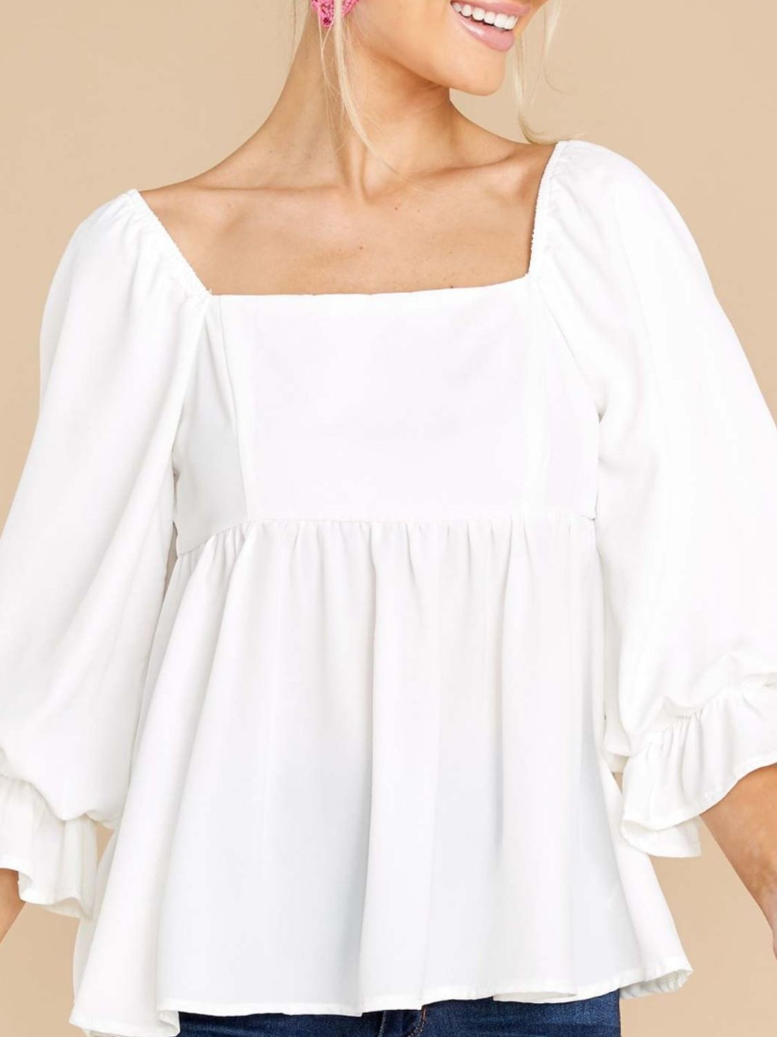 White babydoll blouse with square neckline, puff sleeves, and ruffled cuffs.