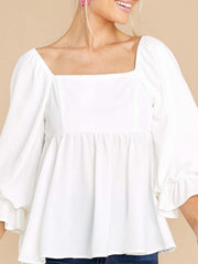 White babydoll blouse with square neckline, puff sleeves, and ruffled cuffs.