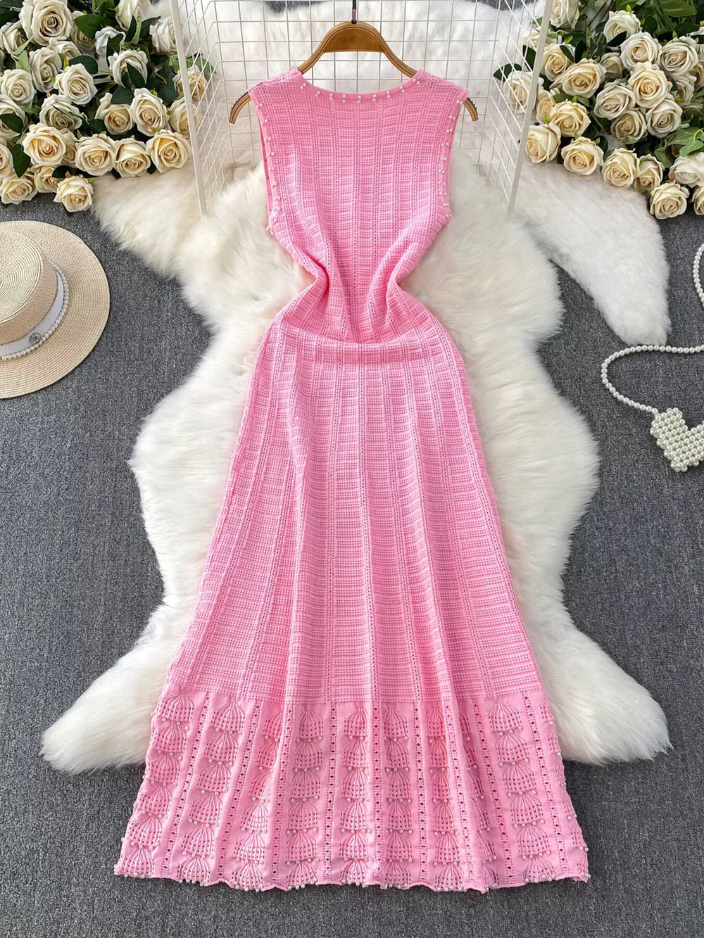 Pink knit midi dress with textured pattern, cutout details, and pearl embellishments.