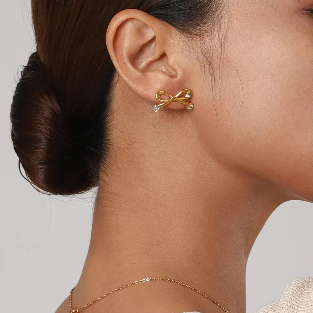 Gold cubic zirconia bow stud earrings with clear crystal accents.