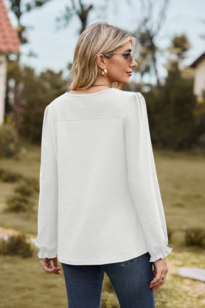 White waffle knit blouse with perforated details and ruffled cuffs.