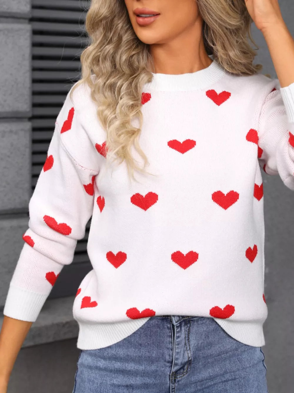 White acrylic knit sweater with a red heart print, crew neck, and long sleeves.