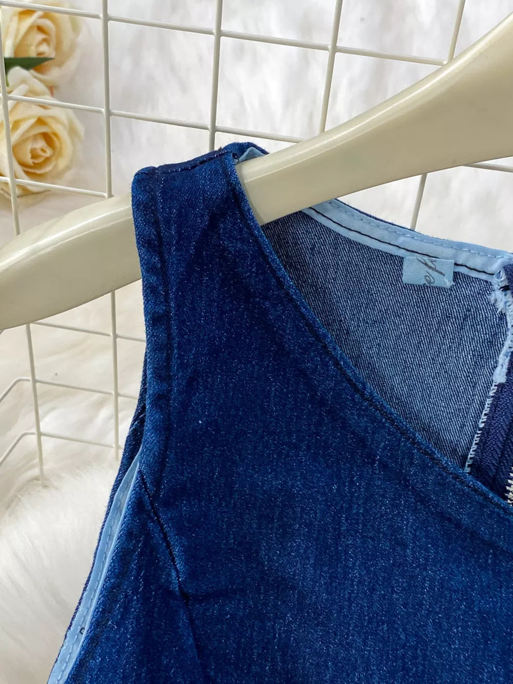 Dark blue cotton denim vest with asymmetrical neckline and zipper detail.