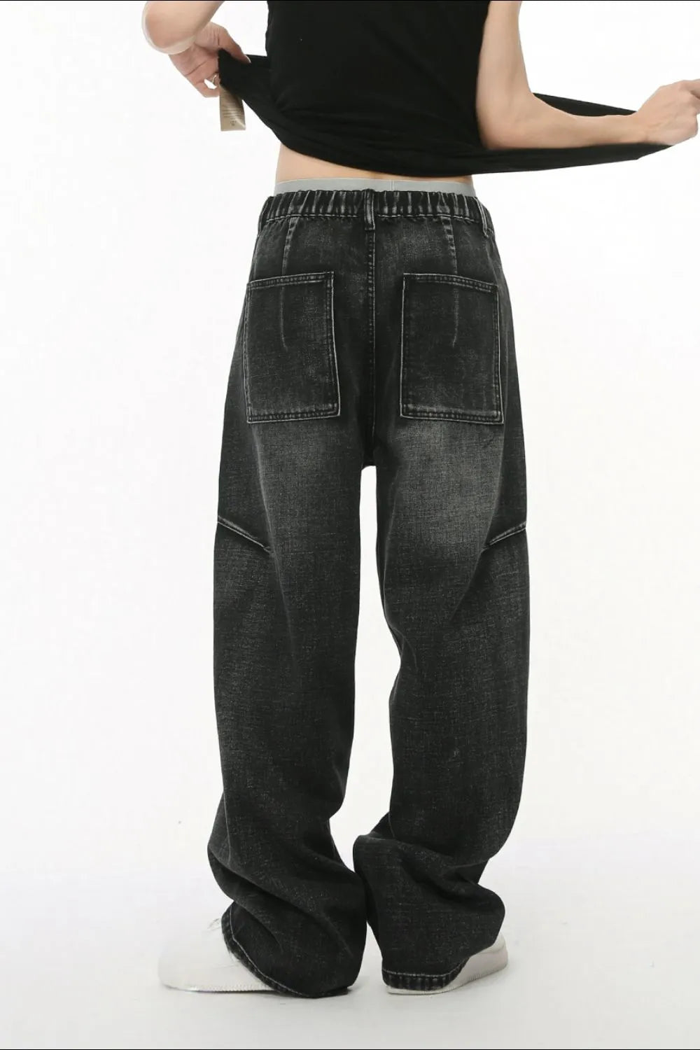 Dark wash denim trousers with exaggerated seam details and large back pockets.