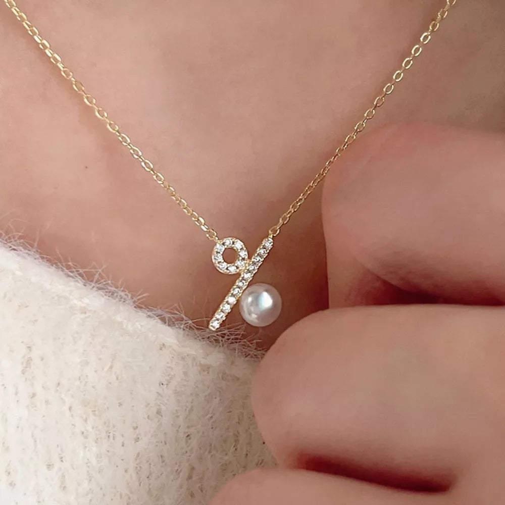 Gold percentage pendant necklace with cubic zirconia and pearl detail.