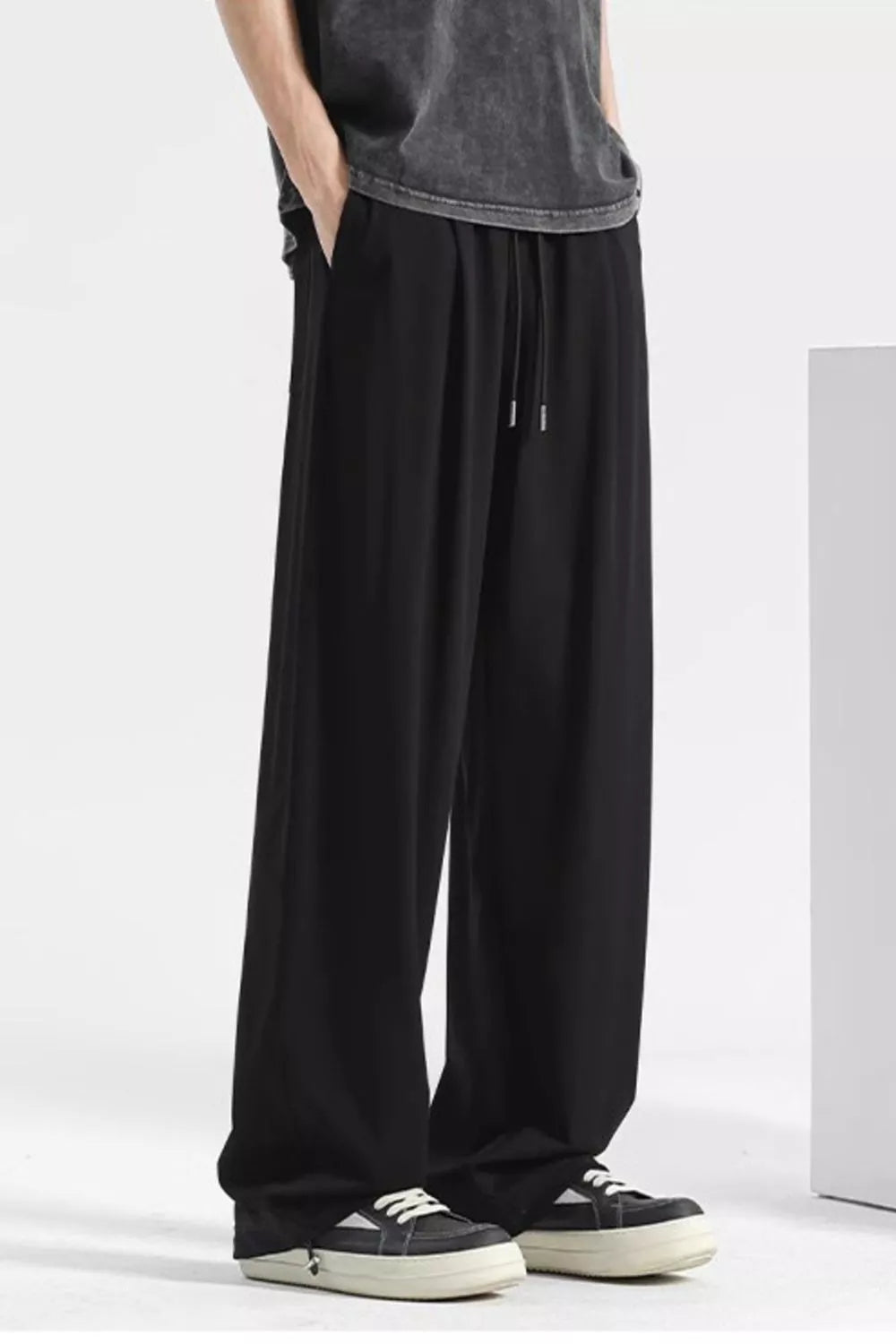 Black sweatpants with drawstring and pockets, styled with a t-shirt and sneakers.