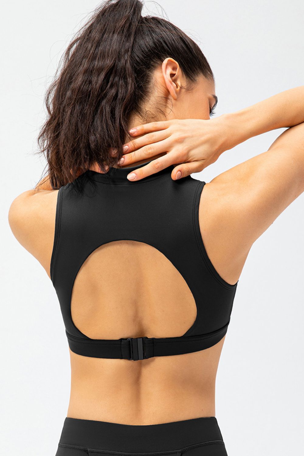 Black high-neck zip-front active crop top with back cutout and adjustable strap.