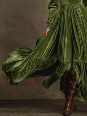 Dark green velvet maxi dress with voluminous sleeves and ruffled hem, styled with brown boots.